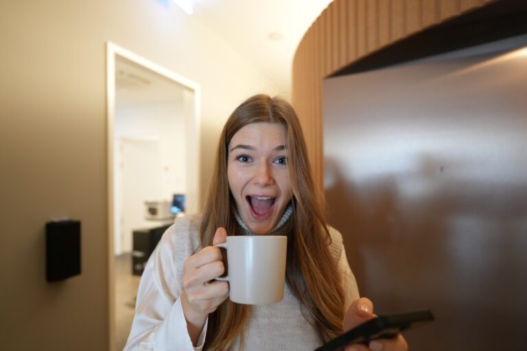 Teammitglied lacht mit Kaffeetasse in die Kamera