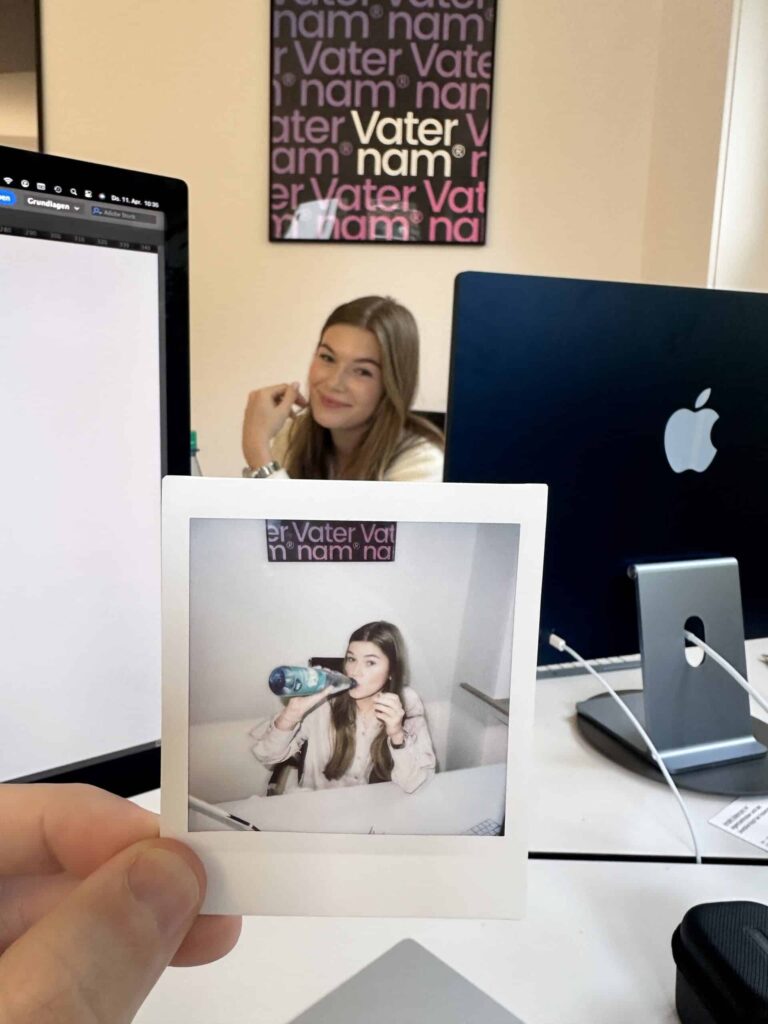 Polaroid von Johanna beim Trinken, dahinter Johanna im Vaternam-Büro
